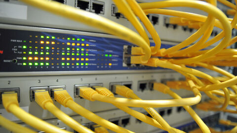 Hinterer Teil eines Rechners, aus dem ganz viele Kabel herausschauen