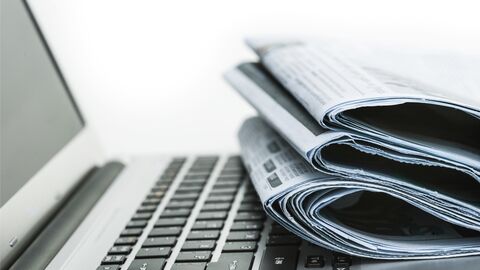 Zeitungen liegen neben einem Laptop. Zeitungen liegen neben einem Laptop.