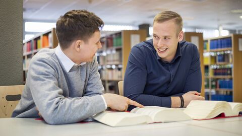 Zwei Männer sitzen in einer Bibliothek