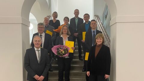 Die ernannten Richterinnen und Richter stehen gemeinsam mit Justizministerin Kühne-Hörmann in einem Torbogen, nach hinten auf Stufen verteilt und lächeln in die Kamera.