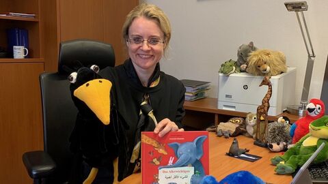 Justizstaatssekretärin liest für die Kinder der Katholischen Kindertagesstätte St. Kilian Justizstaatssekretärin Tanja Eichner hält ein Buch in die Kamera und lächelt