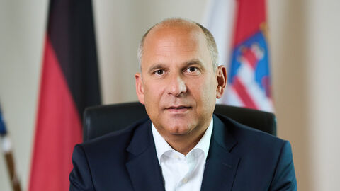 Portrait von Justizminister Prof. Dr. Roman Poseck sitzend an einem Tisch.