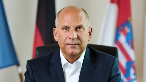 Portrait von Justizminister Prof. Dr. Roman Poseck sitzend an einem Tisch.