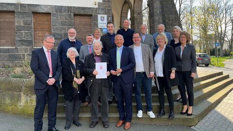 Justizminister Roman Poseck unter anderem mit dem Jubilar Horst Schmidt sowie dessen Ehefrau , Direktor des Amtsgerichts Wetzlar Dr. Achim Lauber-Nöll, Bürgermeisterin der Gemeinde Lahnau Silvia Wrenger-Knispel sowie weiteren Gästen auf einer Treppe, alle schauen in die Kamera..