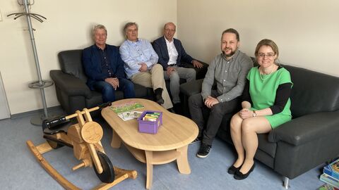 Justizstaatssekretärin Eichner sitzt mit vier weiteren Personen auf einem schwarzen Sofa an einem Tisch, alle lächeln in die Kamera.