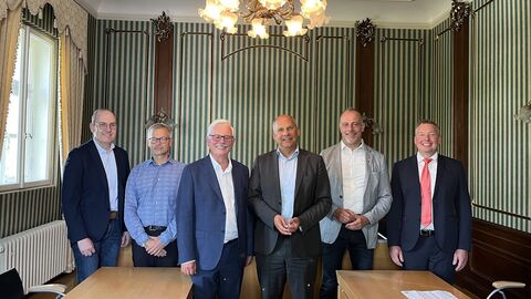 Justizminister Poseck (Mitte) mit weiteren Personen vor einem Tisch in einem Saal des Amtsgerichts