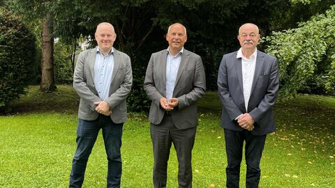 Justizminister Poseck (mitte) mit Dr. Gunnar Formann (links) und Dr. Robert Horn (rechts). Sie stehen nebeneinander auf einer Wiese.