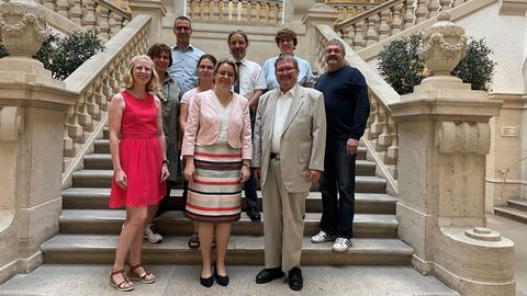 Justizstaatssekretärin Tanja Eichner mit der Leitung und Mitarbeitenden des Amtsgerichts Darmstadt auf einer Treppe im Gerichtsgebäude.