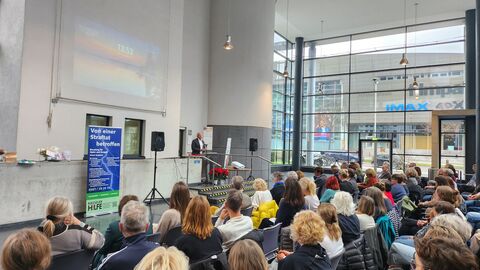 Justizminister Poseck steht vor vielen Menschen vorne auf der Bühne und spricht.