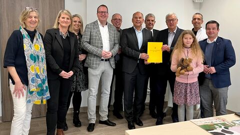 Mehrere Personen stehen gemeinsam zum Gruppenfoto aufgereiht. In der Mitte Justizminister Poseck, der einen Zuwendungsbescheid übergibt.