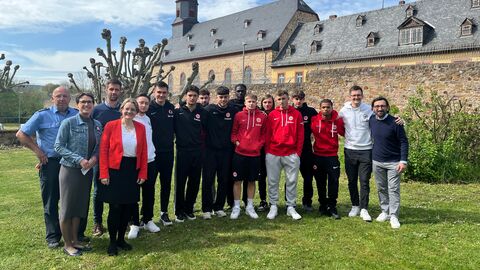 Staatssekretärin Tanja Eichner mit der Jugendmannschaft des Nachwuchsleistungszentrums von Eintracht Frankfurt e. V. Staatssekretärin Tanja Eichner mit der Jugendmannschaft des Nachwuchsleistungszentrums von Eintracht Frankfurt e. V. auf einer Wiese zum Foto aufgestellt.