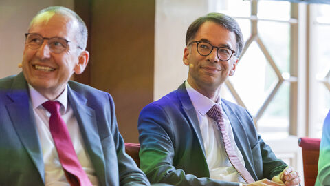 Justizminister Heinz und eine weitere Person sitzen nebeneinander, sie tragen Mikrofone.