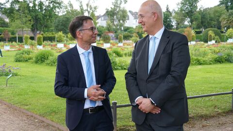 Justizminister Heinz und Dr. Wilhelm Wolf Justizminister Heinz und Dr. Wilhelm Wolf stehen nebeneinander im Gespräch. Im Hintergrund eine Wiese.