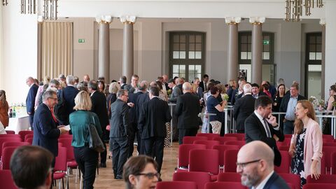 Amtswechselfeier Landessozialgericht Menschen stehen im Saal an den Stehtischen verteilt und unterhalten sich