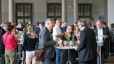 Amtswechselfeier Landessozialgericht Menschen stehen an einem Stehtisch und unterhalten sich