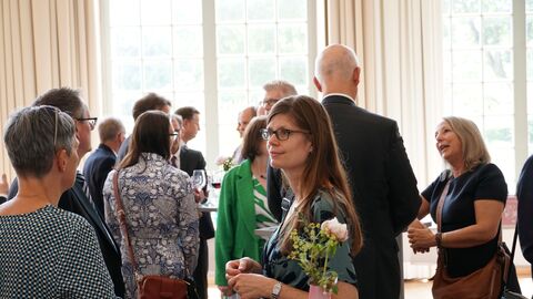 Amtswechselfeier Landessozialgericht Menschen unterhalten sich, trinken ein Glas Sekt und lachen