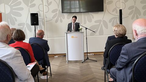 Justizminister Heinz hält eine Rede und steht an einem Rednerpult