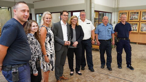 Justizminister Heinz steht zwischen 7 Männern und Frauen. Sie stehen nebeneinander.