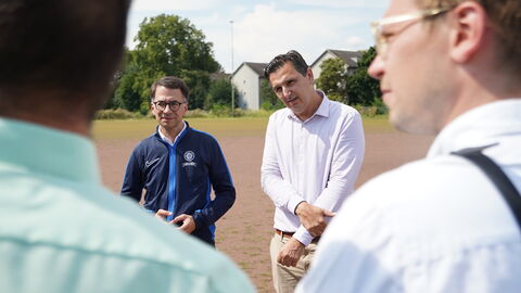 Justizminister Christian Heinz und Oberstaatsanwalt Konstantinos Passialis Justizminister Christian Heinz steht neben Oberstaatsanwalt Konstantinos Passialis auf einem Bolzplatz. Sie sind im Gespräch mit weiteren Personen.