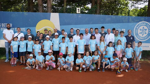 Justizminister Heinz besucht TuS Makkabi Frankfurt e. V. Jusitzminister Heinz zum Gruppenfoto mit einer großen Gruppe Kinder und Trainerinnen und Trainer der TuS Makkabi Frankfurt e. V. aufgestellt. Die Kinder haben Tennisschläger in Händen.