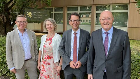 Justizminister Heinz steht mit drei Personen vor dem Landgericht Marburg.