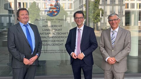 Christan Heinz steht mit zwei weiteren Personen vor einem Gebäude.