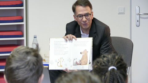 Vorlesen schafft Zukunft Mann zeigt Kindern ein Kinderbuch