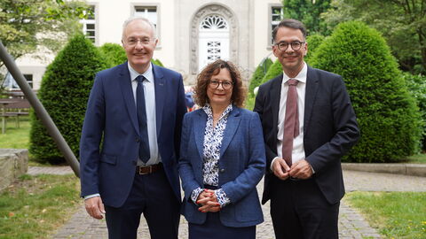 Patricia Evers ist neue Präsidentin des Verwaltungsgerichts Wiesbaden Zwei Männer und eine Frauen stehen nebeneinander. Im Hintergrund ist ein helles Gebäude und grüne Hecken.