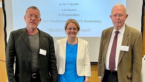 Justizstaatssekretärin Eichner steht mit zwei Personen zum Gruppenfoto aufgestellt.