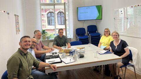 Justizstaatssekretärin Tanja Eichner und Verein für individuelle Erziehungshilfen e. V. Sechs Personen sitzen an einem Tisch und schauen in die Kamera.