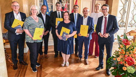 Ehrung für langjähriges Engagement in der hessischen Justiz Mehrere Menschen stehen zusammen, einige halten gelbe Mappen in den Händen.