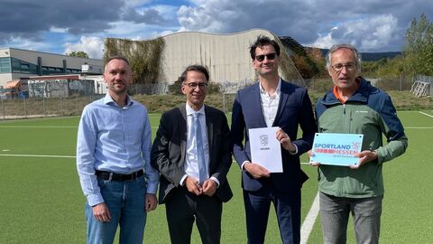 Vier Männer stehen nebeneinander auf einem Fußballfeld.