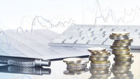 Auf dem Bild sind ein Stift, Münzen und Papier auf grauem Hintergrund zu sehen. Auf dem Bild sind ein Stift, Münzen und Papier auf grauem Hintergrund zu sehen.